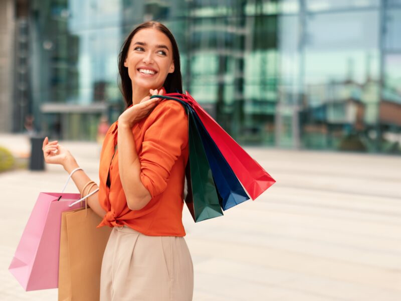 Woman holding shopping bags and smiling at Heritage Grove