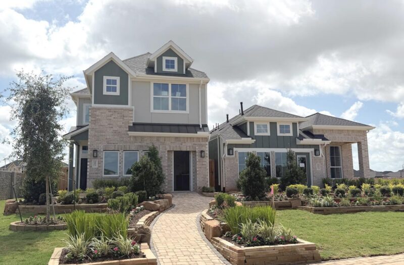 Two modern Chesmar Homes in Fulshear with landscaped yards under a partly cloudy sky.